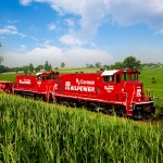 Railpower locomotives travel through fields and pastures.